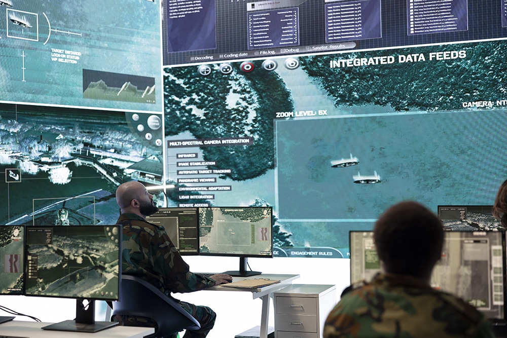 Army personnel monitoring surveillance imagery from satellite system